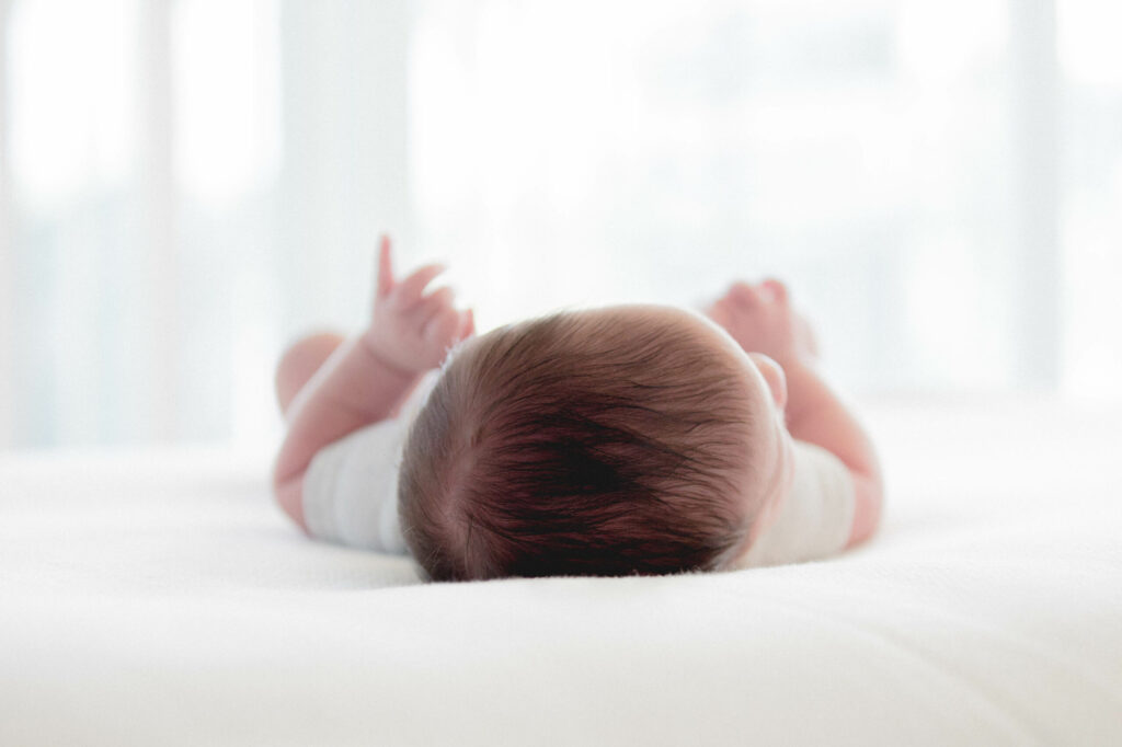 Picture of a baby lying on its back, face turned away from the viewer so mainly the top of the head is visible. Funded by the German Society for Ultrasound in Medicine (DEGUM) with 180,000 euros, FAU researchers are hoping to develop a new method to examine the brains of newborns by combinging new high-speed ultrasound devices with AI Imaging. The high resolution images could help detect stroke and and aspyhxia in babies.